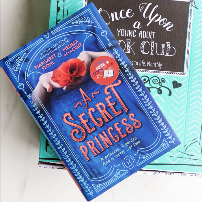 a hardcover edition of "A Secret Princess" by Margaret Stohl and Melissa de la Cruz sits on a green box