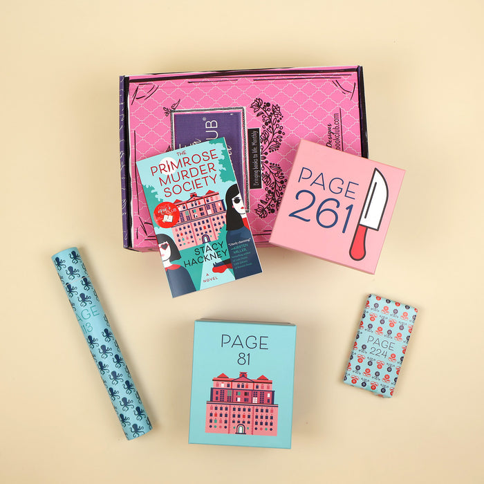 A paperback copy of The Primrose Murder Society by Stacy Hackney lays on a pink OUABC box and is surrounded by four wrapped gifts labeled with page numbers.