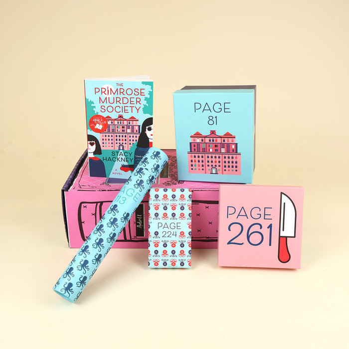 A paperback copy of The Primrose Murder Society by Stacy Hackney stands on a pink OUABC box and is surrounded by four wrapped gifts labeled with page numbers.