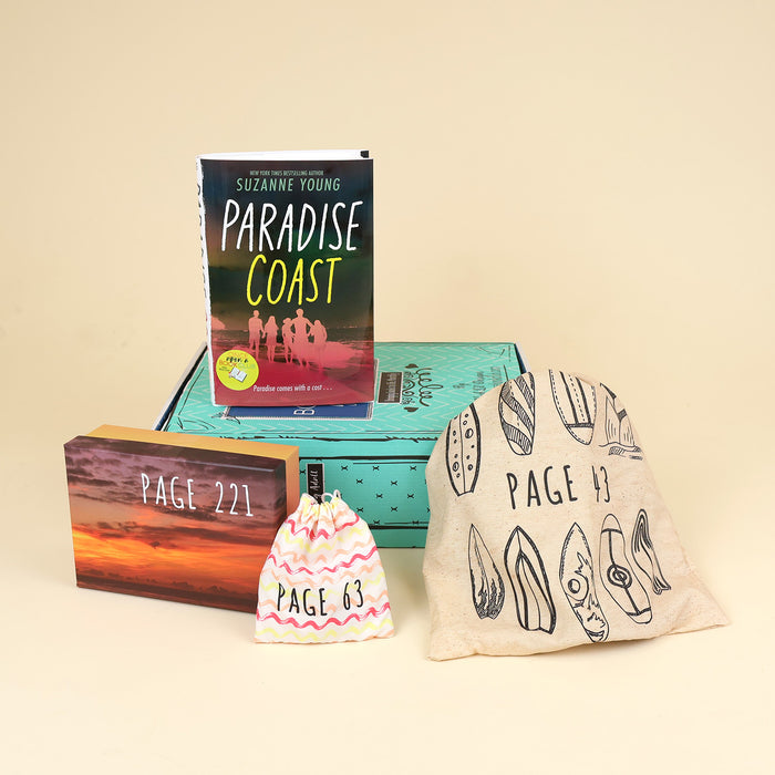 A hardcover copy of Paradise Coast by Suzanne Young lays on a green OUABC box and is surrounded by three wrapped gifts labeled with page numbers.