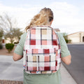 Person wearing a pink plaid backpack outdoors on a sidewalk