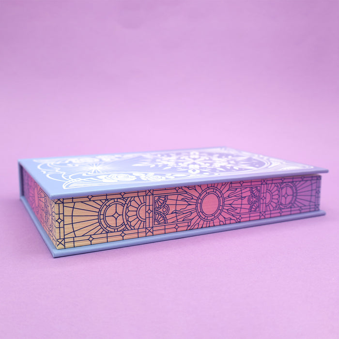 A copy of 'The Sun and the Starmaker'  with stained glass page edges on a purple background